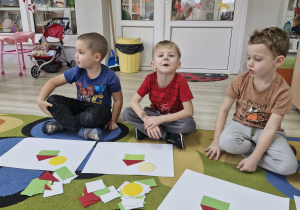 Szymon, Oluś i Marcel układają obrazki według instrukcji słownej.
