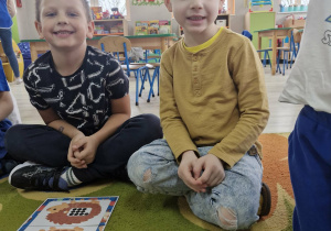 Franek i Marcel siedzą na dywanie. Przed nimi leżą ułożone jeżykowe karty matematyczne.