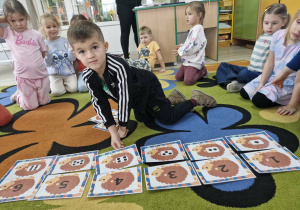 Staś trzyma w dłoniach kartę z wizerunkiem jeża z 4 kropkami i dopasowuje ją do karty z cyfrą 4.