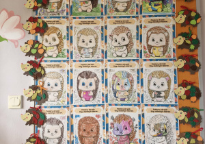 Tablica korkowa, na której wiszą prace plastyczne z wizerunkami jeży wykonane przez dzieci.