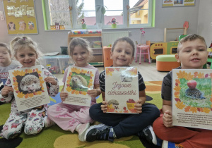 Liliana, Klara, Franuś i Oskar trzymają w dłoniach karty z ciekawostkami o jeżach.
