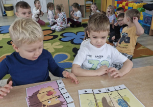 Karol i Ignacy układają obrazki pocięte na kilka części.