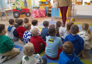 Pani Agata stoi przed dziećmi i opowiada o pracy rolnika. W tle banery o tematyce wiejskiej.