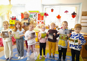 Grupka dzieci wraz z Panią Agatą prezentuje zdjęcia zwierząt oraz ich domy.