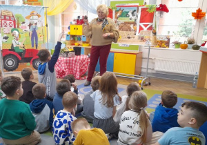 Dzieci siedzą na dywanie, a Pani Agata prezentuje dzieciom warzywa.