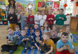 "Słoneczka" pozują do wspólnego zdjęcia z zaproszonymi gośćmi. Dzieci trzymają mini słoiczki z miodem. W tle banery z motywem wiejskim.