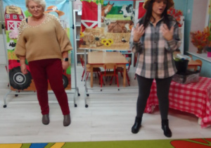 Pani Agata i jej córka opowiadają dzieciom o pracy rolnika, z tyłu banery z dekoracją.