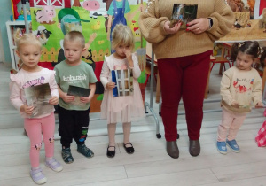 Kornelia, Szymon, Emilia, Pani Agata i Hania prezentują obrazki przedstawiające "domy" zwierząt gospodarskich. W tle dekoracja.