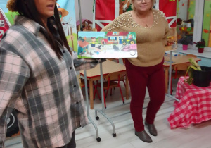 Pani Agata i jej córka prezentują dzieciom książeczkę o wsi, która dodatkowo wydaje odgłosy słyszane w gospodarstwie rolnym.