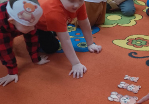 Grupka czterech chłopców ogląda misie ułożone od najmniejszego do największego.