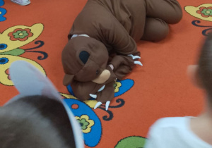 Miś śpi na dywanie, a dzieci chodzą w kole i śpiewają piosenkę "Stary niedźwiedź".