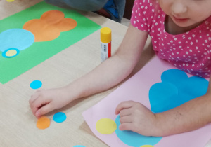 Felicja i Józio z zapałem naklejają misia.