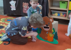 Chłopiec podczas zabawy w karmienie misia miodkiem.