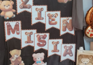 Na tle dekoracji Dzień Misia ustawione w koszyku misiowe ciasteczka.