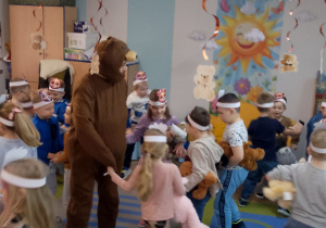 Zabawa taneczna w kółeczkach wspólnie z nauczycielem w stroju misia.