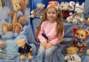 Dziewczynka siedzi na tle dekoracji.