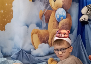 Chłopiec pozuje do zdjęcia na tle dekoracji.