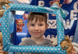 Staś pozuje do zdjęcia w misiowej foto-ramce.