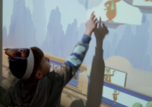 Chłopiec na tablicy multimedialnej wskazuje misia.