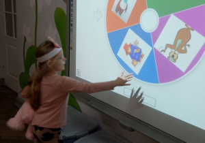 Zuzia na tablicy multimedialnej kręci misiowym kołem fortuny.