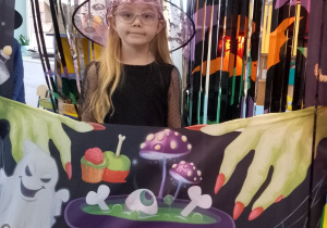 Zuzia pozuje do zdjęcia w andrzejkowej fotobudce.