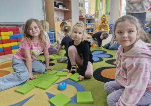 Weronika, Ala i Klara siedzą na dywanie i układają zestaw Go Robot Mouse