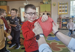 Antoś przebija szpilką papierowe czerwone serce.