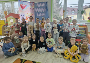 Wspólne zdjęcie dzieci z grupy "Biedronek" z ulubionymi misiami na tle dekoracji w sali.