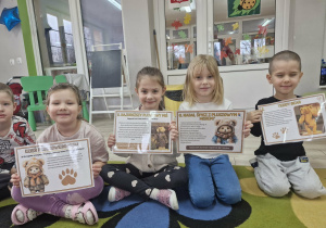 Maja, Oliwia, Nadia i Wojtuś trzymają w dłoniach karty z ciekawostkami o misiach.