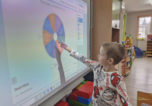 Julek korzysta z tablicy multimedialnej rozwiązując quiz o misiach.