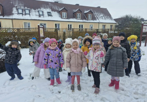 Dzieci bawią się na śniegu w ogrodzie przedszkolnym.