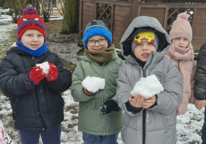 Nikoś, Tymek i Lucjan trzymają w dłoniach śniegowe kule.