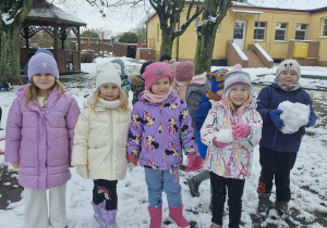 Weronika, Ala, Klara, Nadia i Oskar pozują do zdjęcia w zaśnieżonym ogrodzie przedszkolnym.