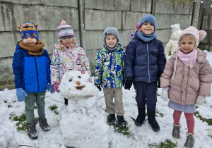 Marcel, Nadia, Oluś, Franuś i Lila pozują do zdjęcia z ulepionym przez dzieci bałwankiem.