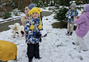 Wojtuś ze śnieżką w dłoni bawi się na śniegu.