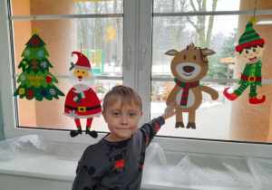 Hubert pokazuje powieszonego przez siebie renifera na oknie.