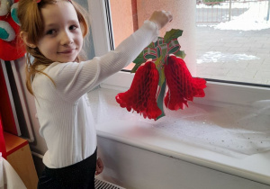 Emma kładzie na parapecie dzwonki z papieru.