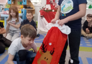 Staś za pomocą dotyku sprawdza co znajduje się w worku, który trzyma Marcel.