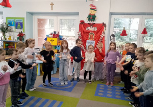 Dzieci stoją w półkolu i śpiewają piosenkę.