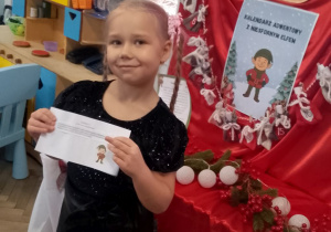 Tosia stoi i pokazuje dzieciom trzecie zadanie z kalendarza.