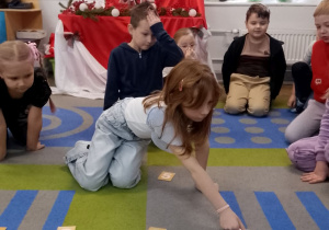 Emma układa na dywanie ilustracje według kolejności zdarzeń.