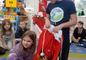 Weronika za pomocą dotyku sprawdza co znajduje się w worku, który trzyma Marcel.