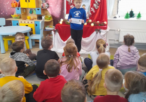 Hubert stoi i pokazuje dzieciom czwarte zadanie z kalendarza adwentowego.