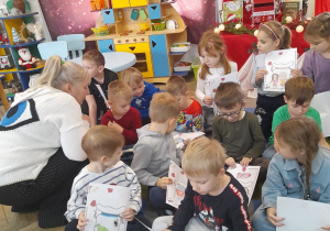 Dzieci siedzą na dywanie, a Pani z biblioteki przykucnęła obok i rozmawia z przedszkolakami o ich marzeniach.