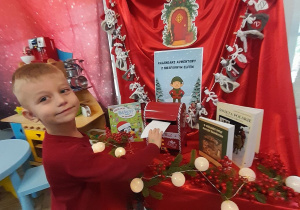 Wiktor stoi obok tablicy z kalendarzem adwentowym i szafki, na której stoi "magiczna skrzynka". Chłopiec wrzuca do niej wykonany list do Świętego Mikołaja".