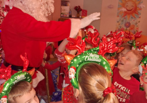 Dzieci stoją w rozsypce i żegnają się z Mikołajem.