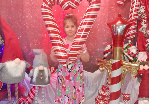 Nadia pozuje do zdjęcia z biało-czerwonymi balonowymi laskami. W tle dekoracja.