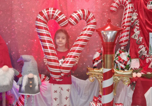 Amanda pozuje do zdjęcia na tle dekoracji z biało-czerwonymi balonowymi laskami.