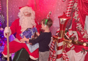 Staś odbiera od Mikołaja prezent.