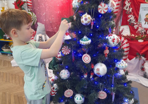 Staś zawiesza bombkę na choince.